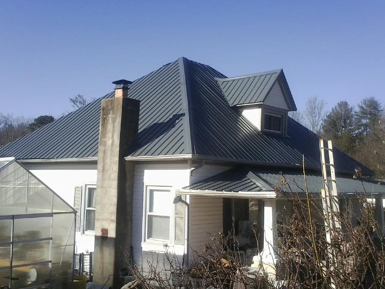 Dark blue standing seam metal roof on a white farmhouse with dormer — Slate & Tile Roof Repair by Roofing Brothers in Lake Villa