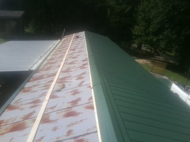 Old rusted panels beside newly installed green metal roofing — Wind Damage Roof Repair by Roofing Brothers in Lake Villa