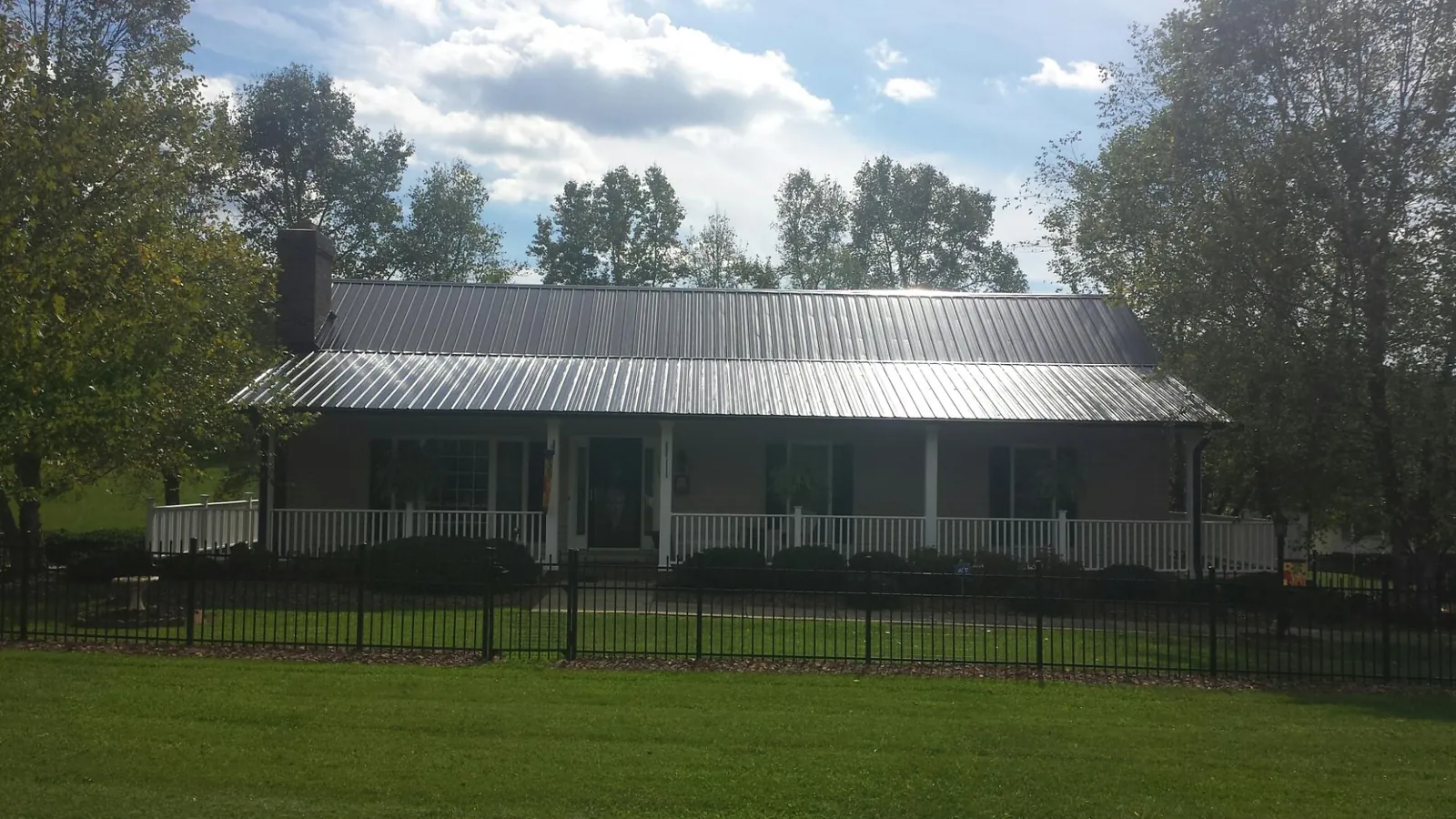 Gray metal roof on a brick ranch with a full width front porch — Gutter Guard Installation work by our crew in Lake Villa