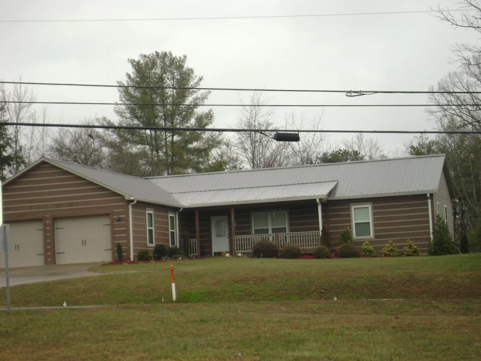 Gray metal roof on a log sided ranch home with a front porch in Lake Villa