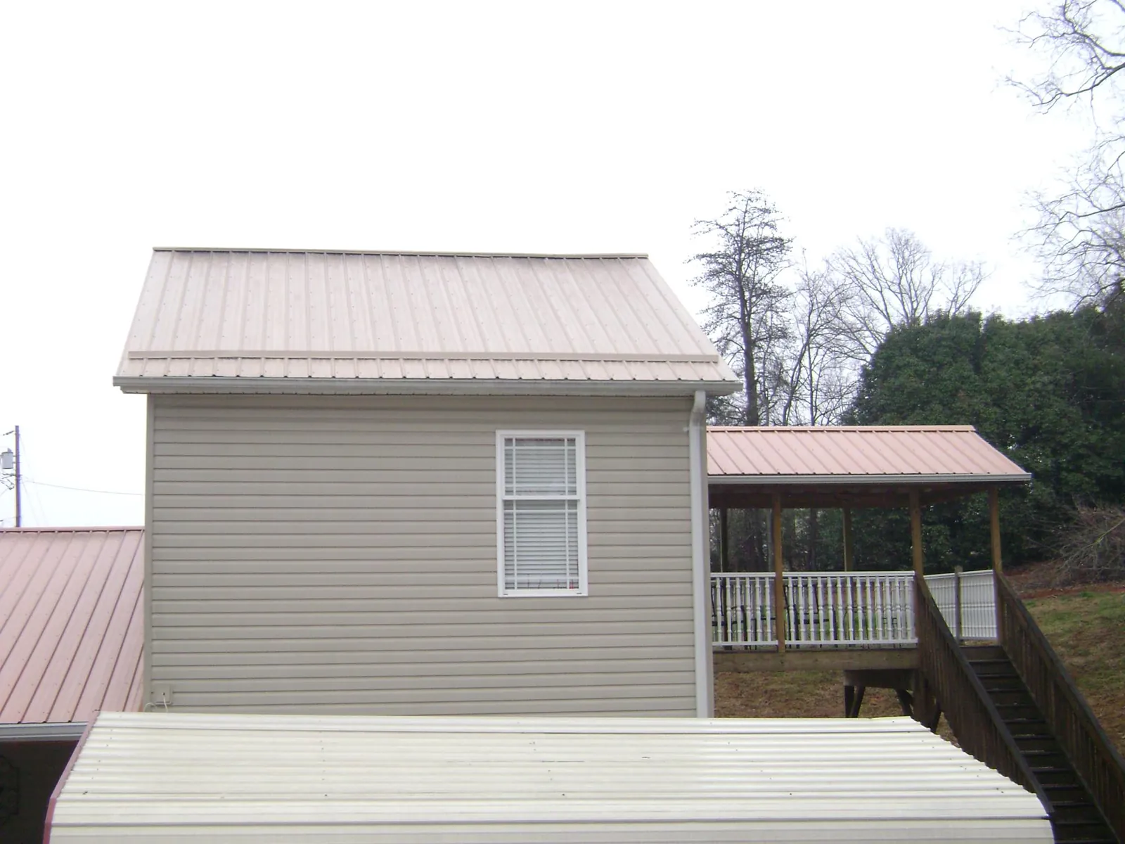 Tan metal roofs on a two story addition and attached porch, from a Roof Replacement job in Lake Villa