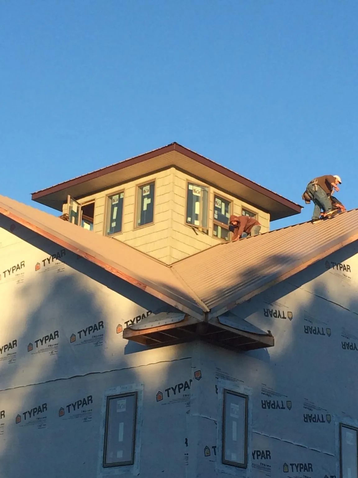 Roofers working around a rooftop cupola on a new metal roof at sunset — Roof Waterproofing in Lake Villa by Roofing Brothers